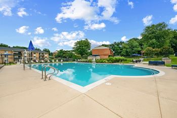A large outdoor swimming pool with a blue sky and clouds in the background.